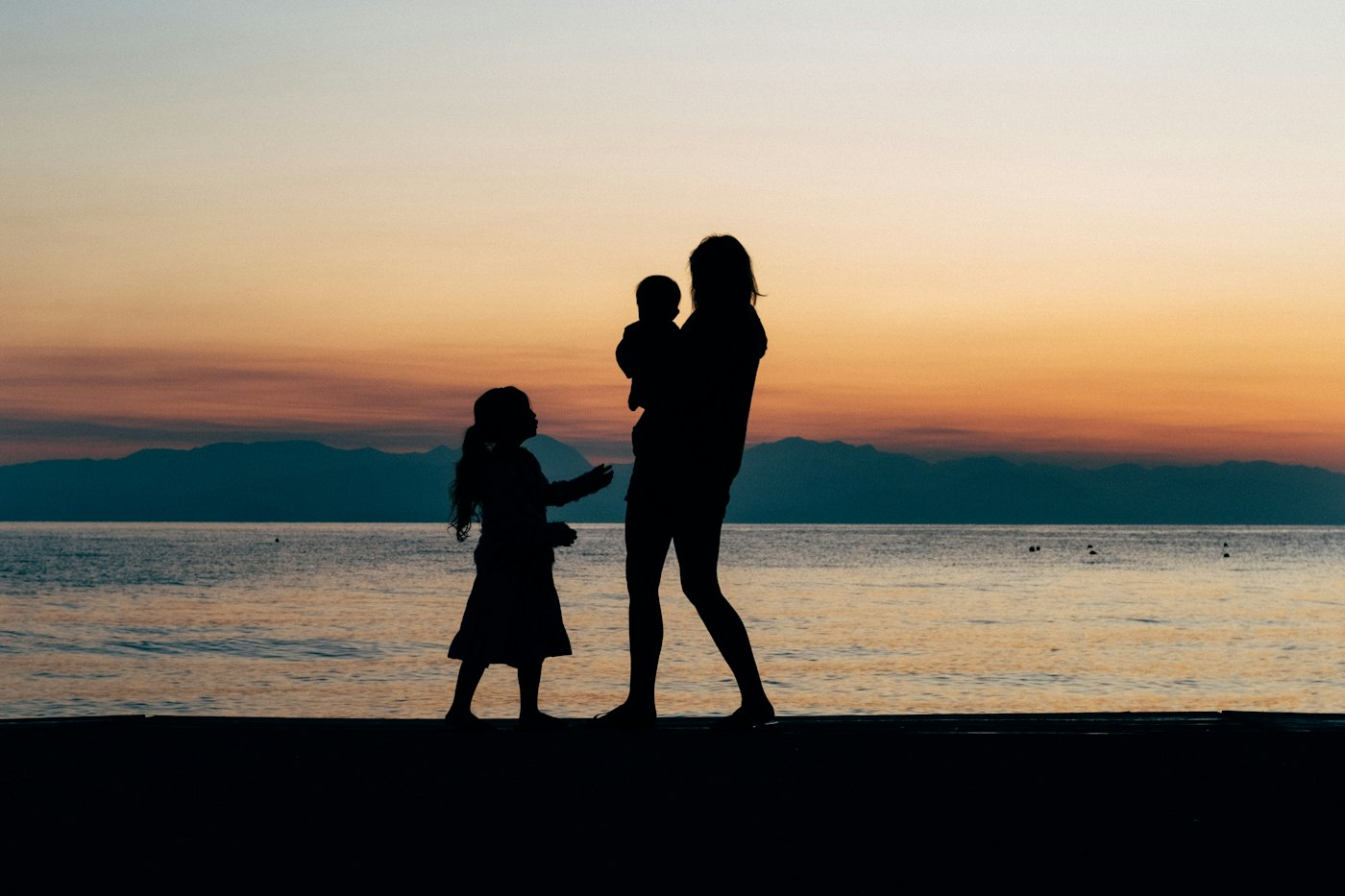 Mother and children beside the sea at sunset in Greece
